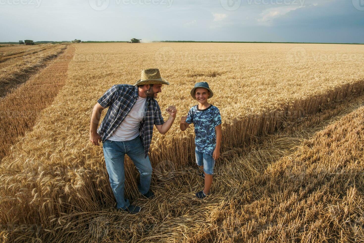 pai e filho estão em pé dentro seus trigo campo foto