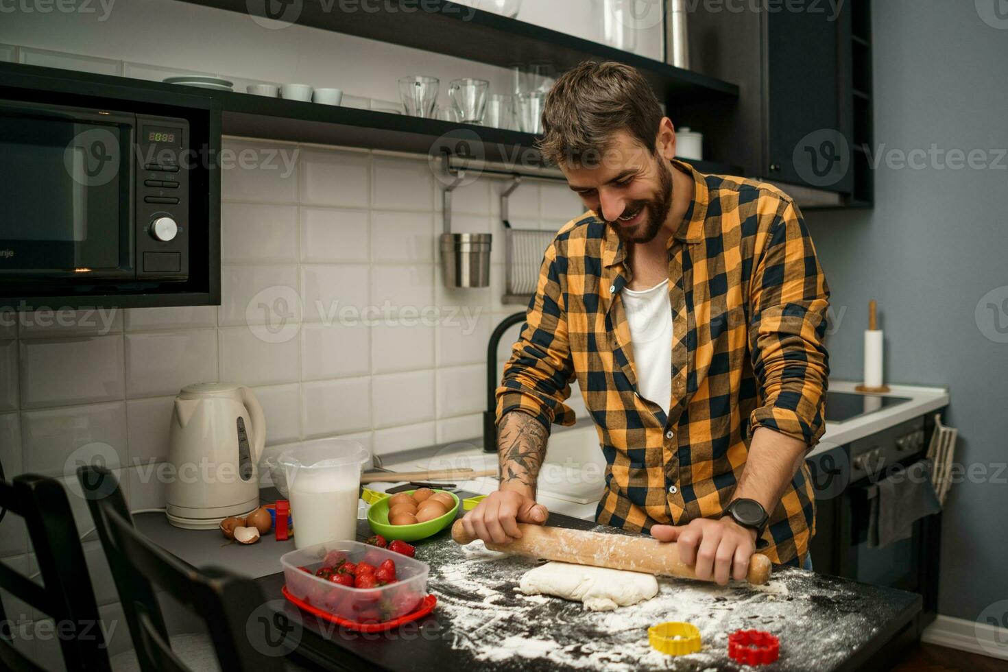 uma homem cozimento biscoitos dentro a cozinha foto