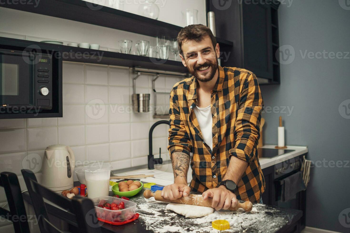 uma homem cozimento biscoitos dentro a cozinha foto