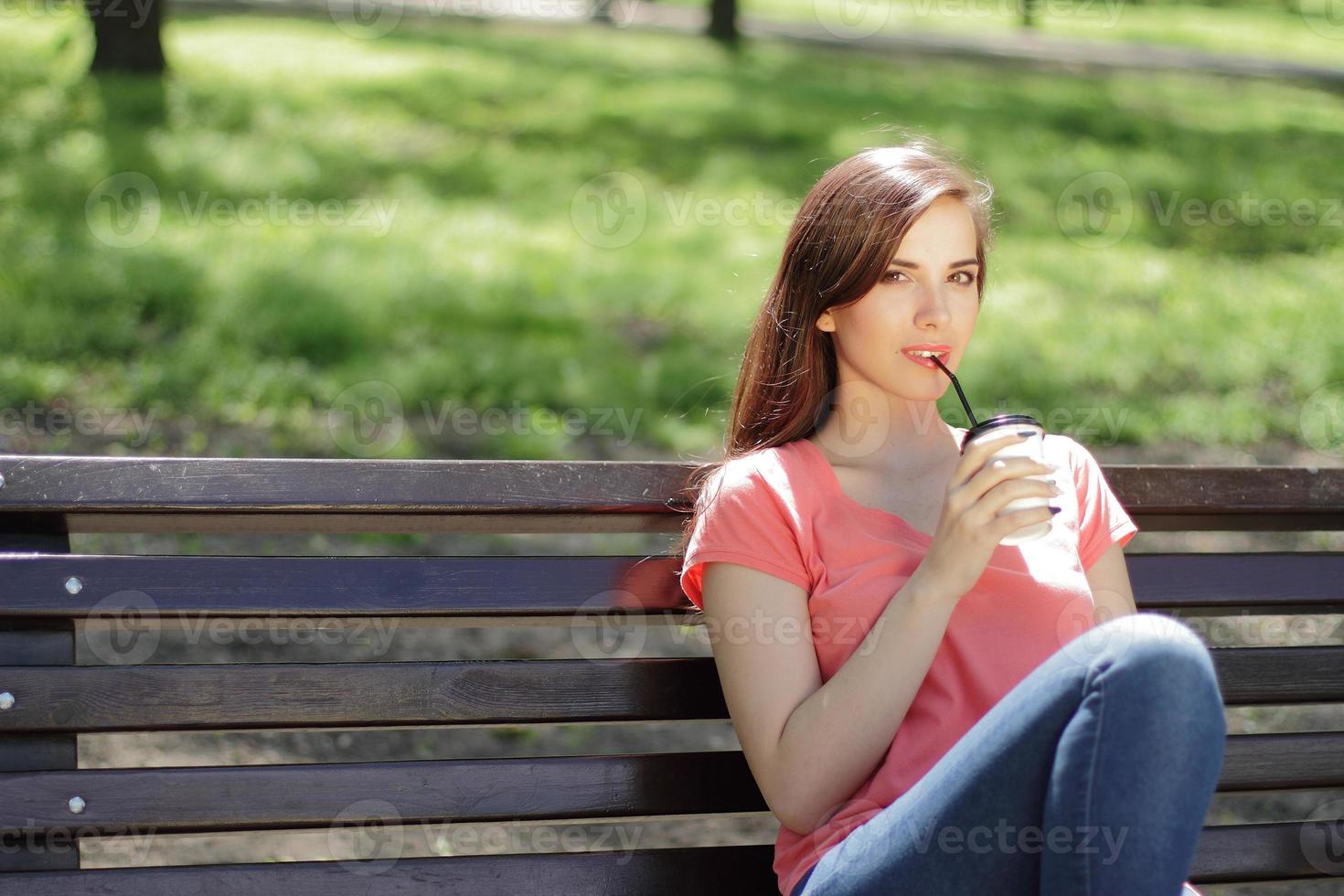 mulher tomando café em um banco do parque foto