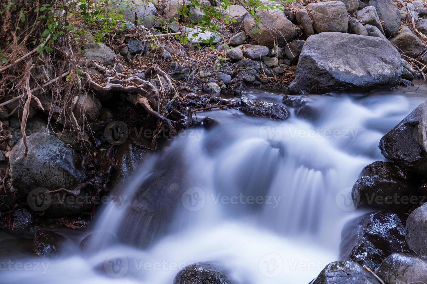 córrego de água pura com fluxo suave em terreno montanhoso rochoso na floresta kakopetria em troodos chipre foto