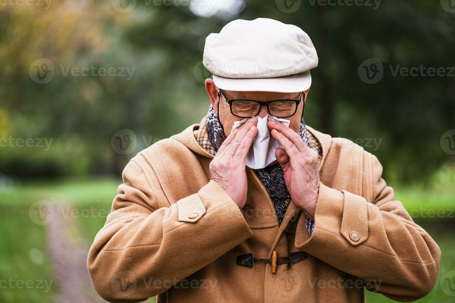 ao ar livre retrato do uma Senior homem dentro inverno casaco sopro dele nariz foto