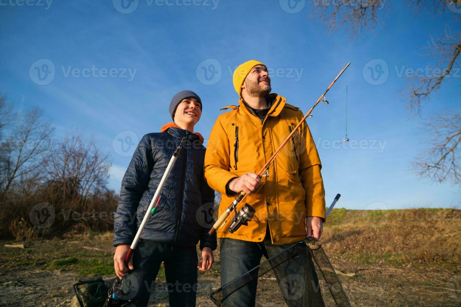 pai e filho estão pescaria em ensolarado inverno dia foto