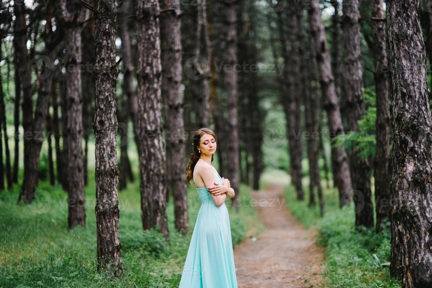 garota feliz em um vestido longo turquesa em um parque verde foto