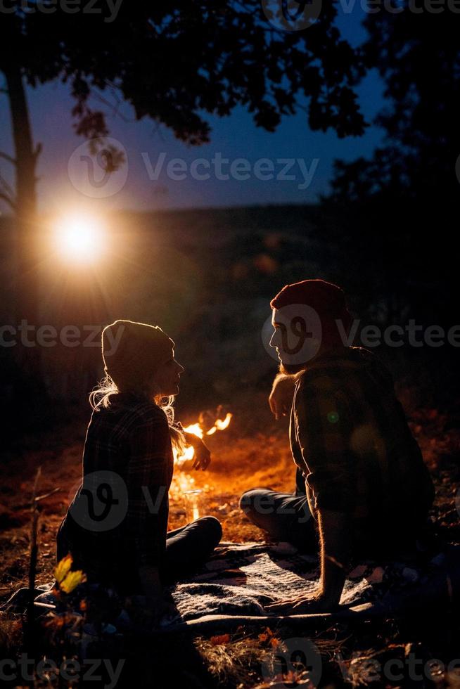 casal jovem, um rapaz e uma rapariga com chapéus de malha brilhantes, pararam num parque de campismo foto