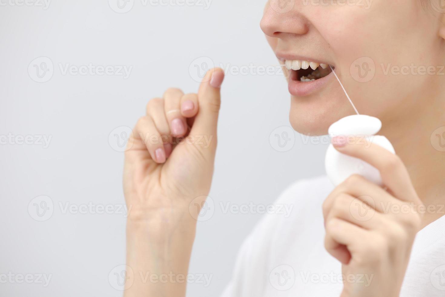 mulheres sorridentes usam fio dental em um fundo branco foto