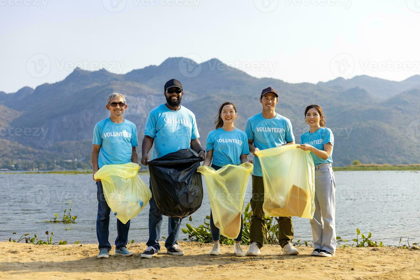 equipe do jovem e diversidade voluntário trabalhador grupo apreciar caridoso social trabalhos ao ar livre dentro limpeza acima lixo e desperdício separação projeto às rio de praia foto