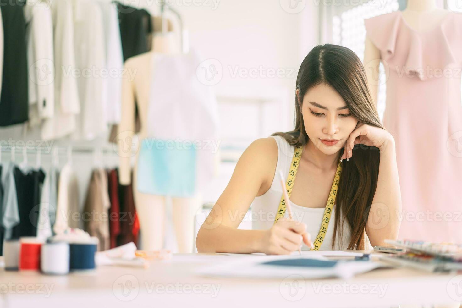 ásia mulher desenhador ocupado fazer roupas trabalhos ou estude dentro moda Projeto estúdio foto