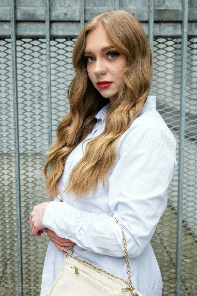 atraente Loiras mulher com grandes cabelos dentro uma branco blusa foto