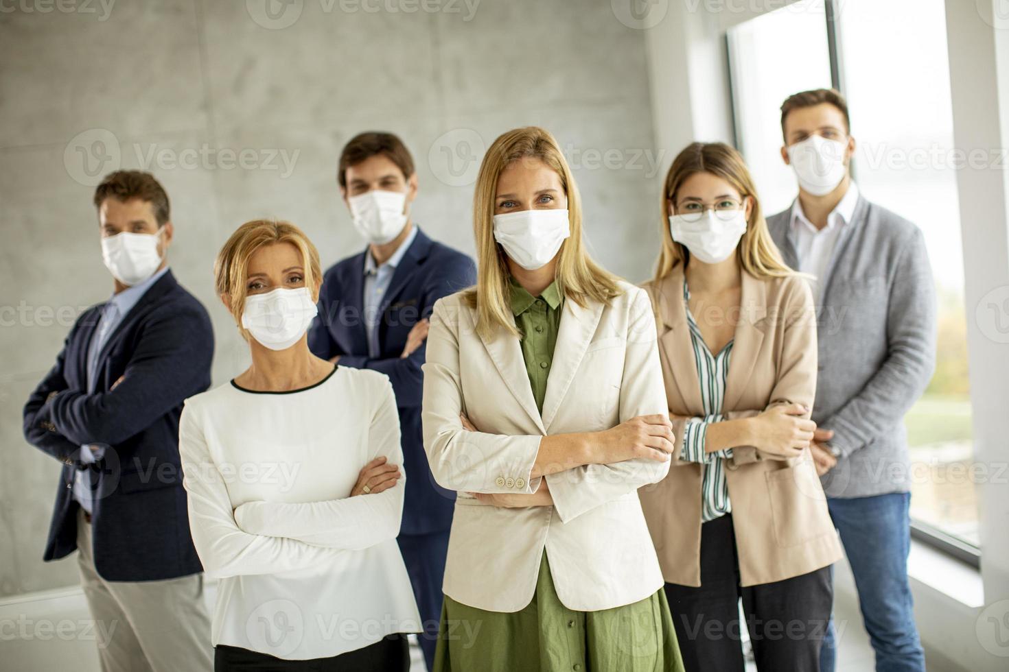 equipe em pé e usando máscaras foto