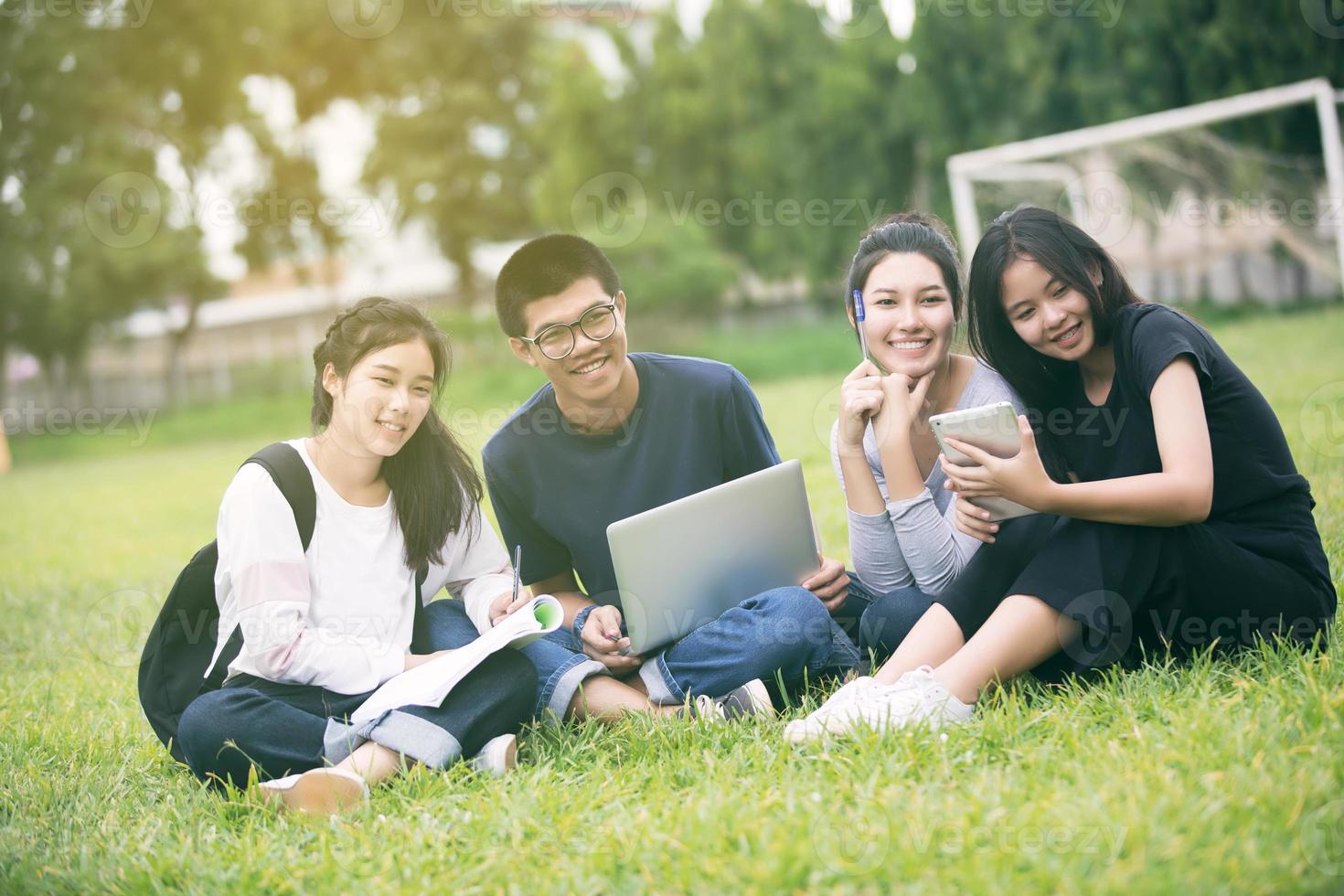 grupo de estudantes asiáticos estudando na grama foto