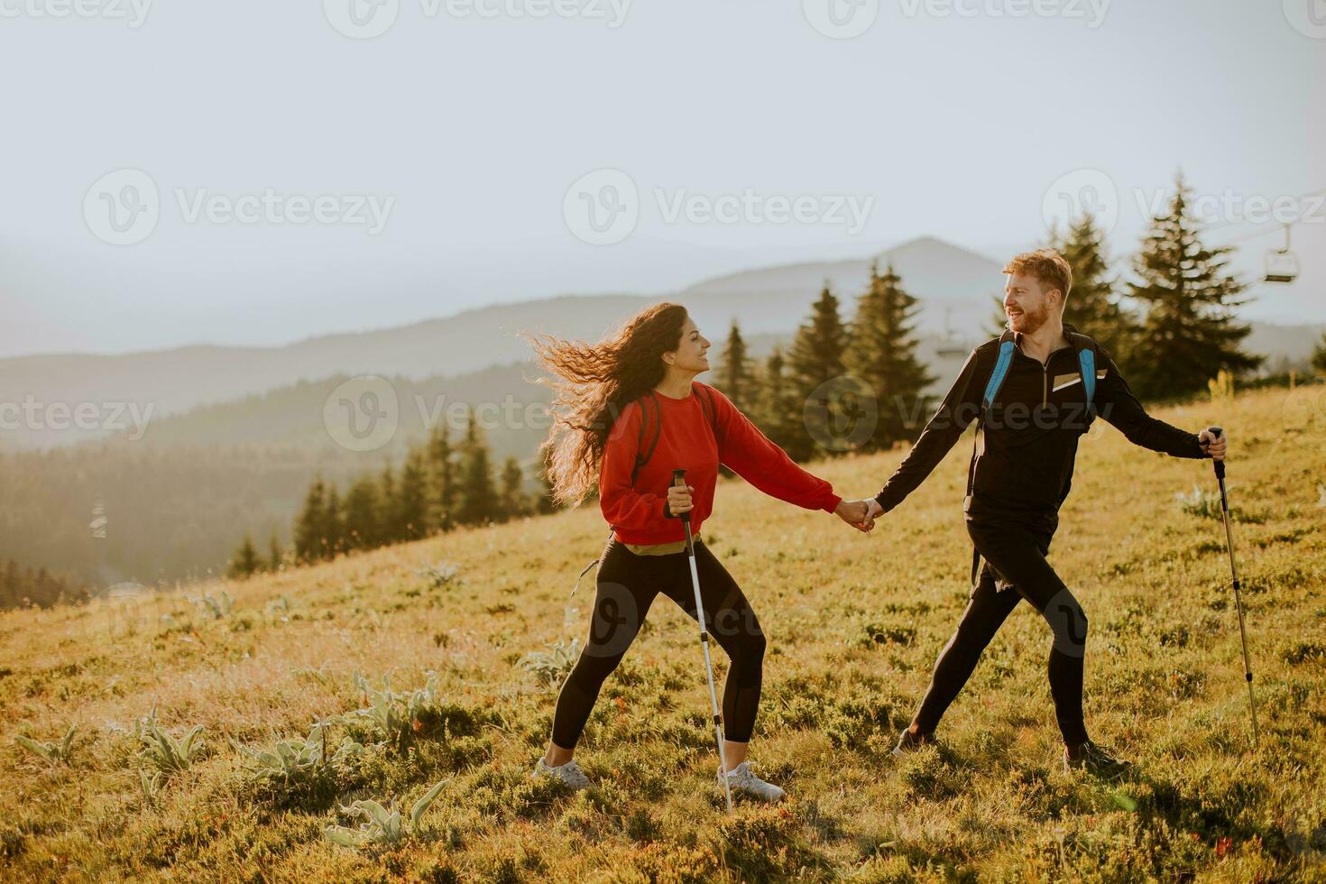 jovem casal caminhando com mochila sobre verde colinas foto