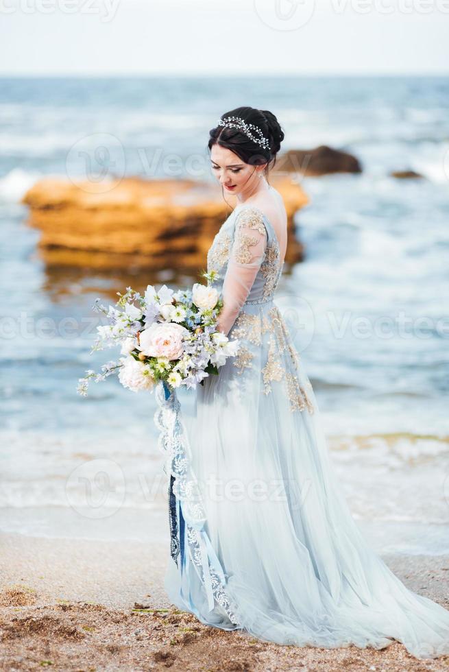 noiva com um buquê de flores na praia foto