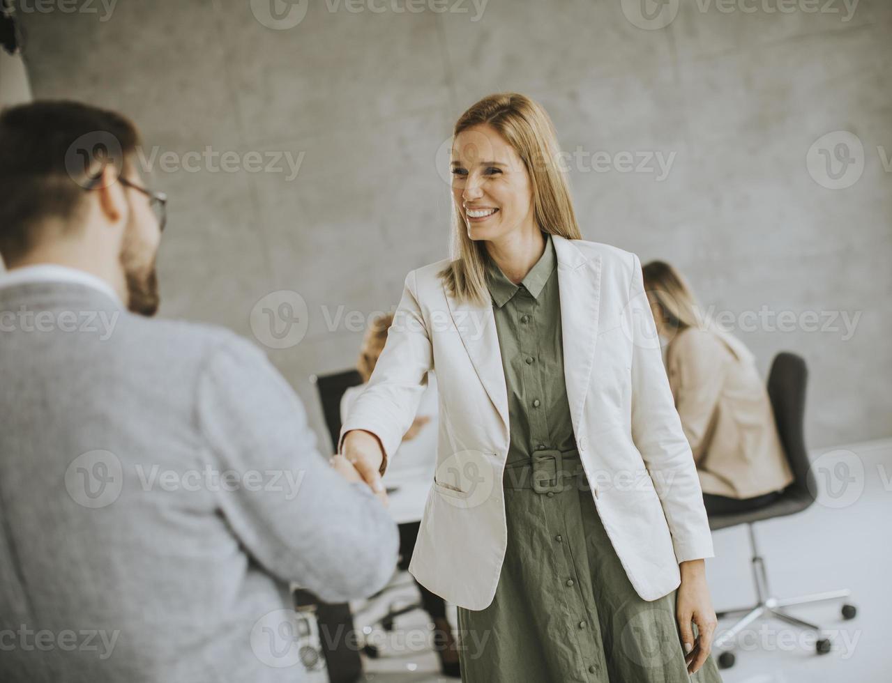 dois profissionais de negócios apertando as mãos em um escritório foto
