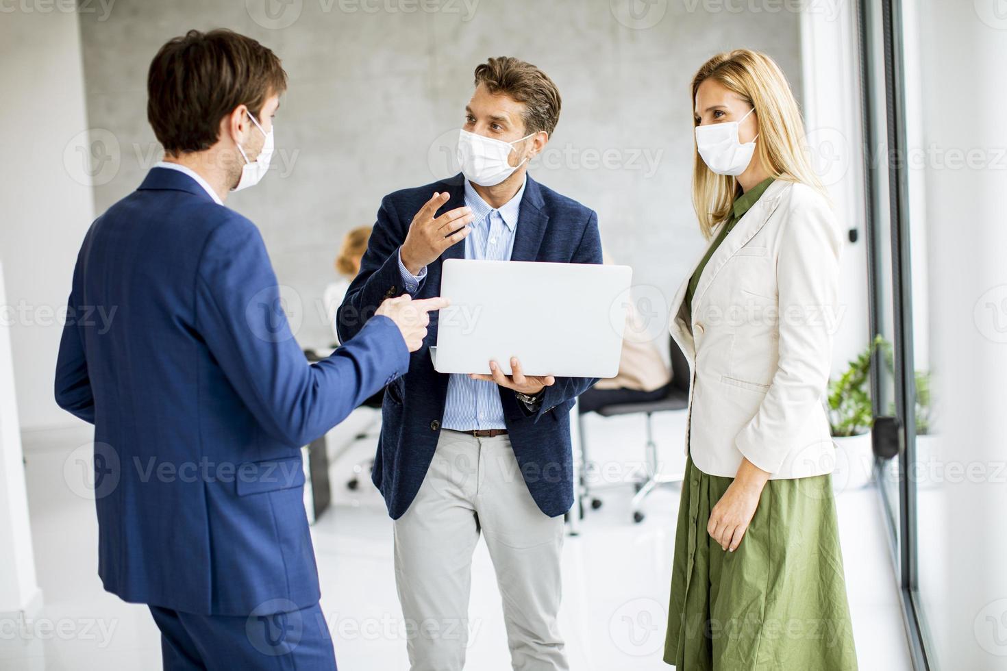 três profissionais mascarados em pé e conversando foto