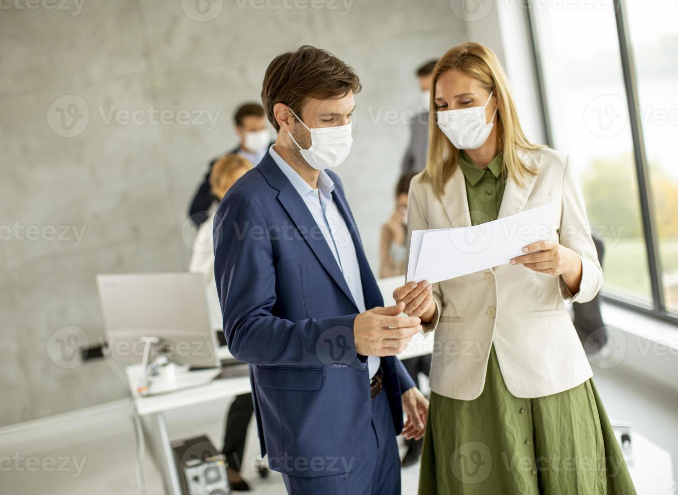 dois profissionais mascarados olhando para um documento foto