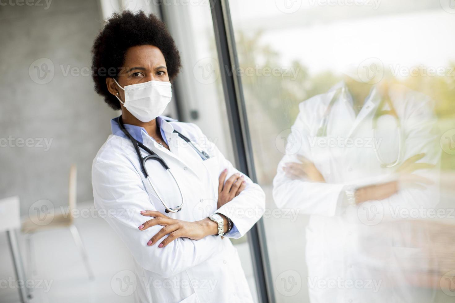 médico com braços cruzados perto da janela foto