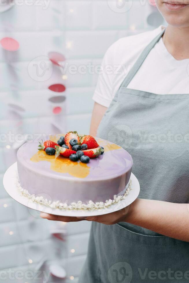 uma lindo mousse bolo dentro a mãos do uma pastelaria chefe de cozinha foto