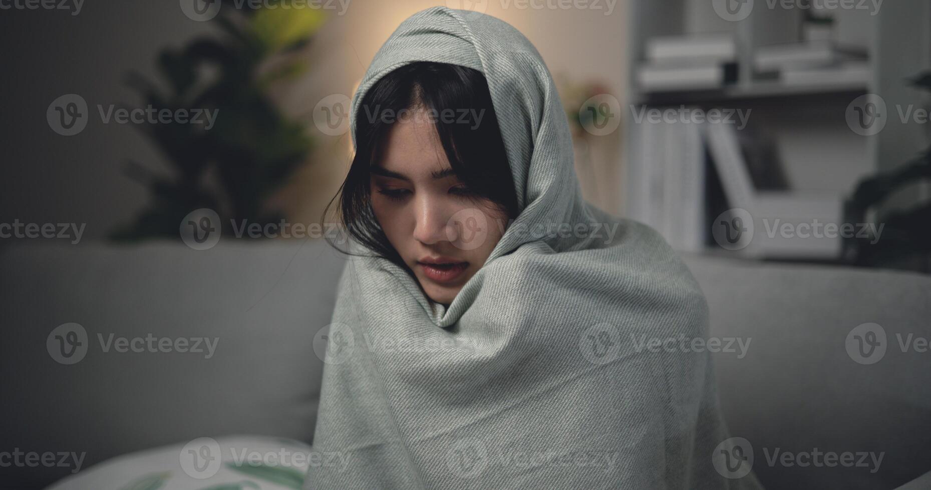 ásia jovem mulher sentado debaixo cobertor com sofrimento a partir de frio e gripe às casa foto