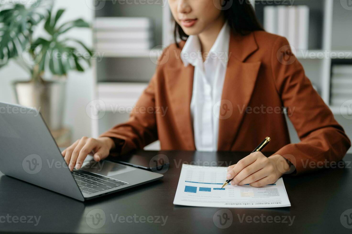 o negócio mulher sentado frente tábua ,computador portátil computador com financeiro gráficos e Estatisticas em monitor. foto