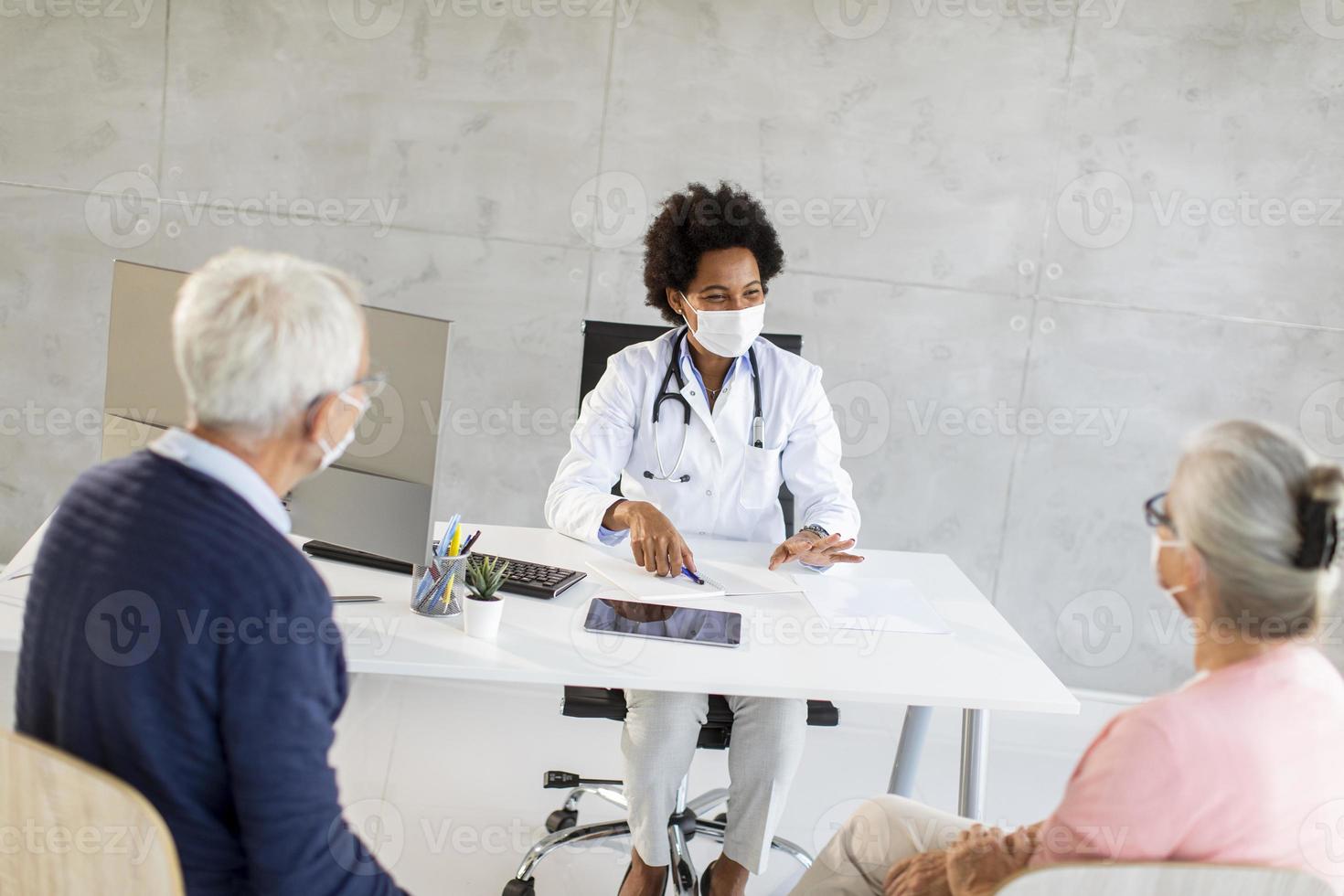 médico conversando com casal maduro usando máscaras foto