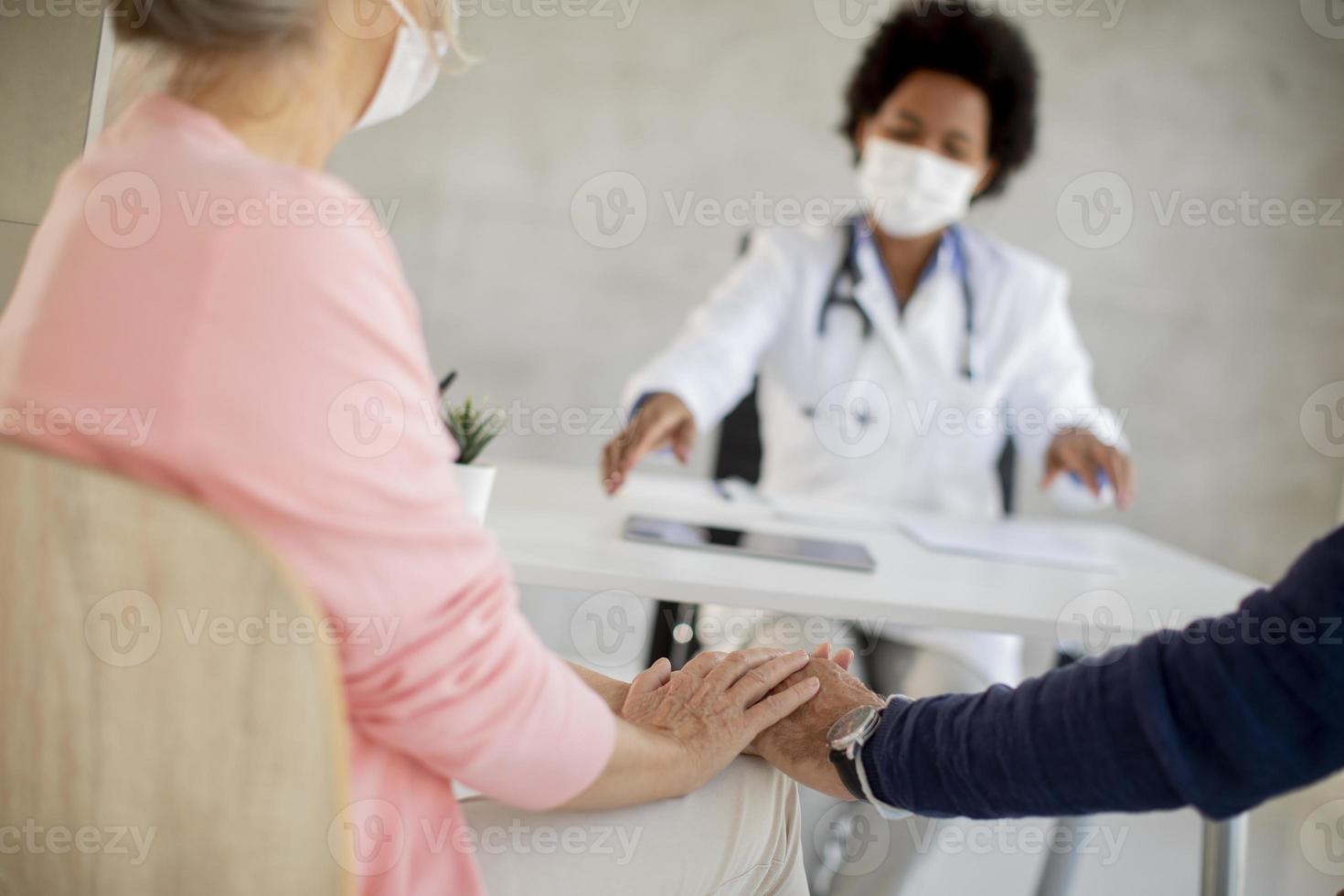 close-up de casal maduro conversando com um médico com máscaras foto