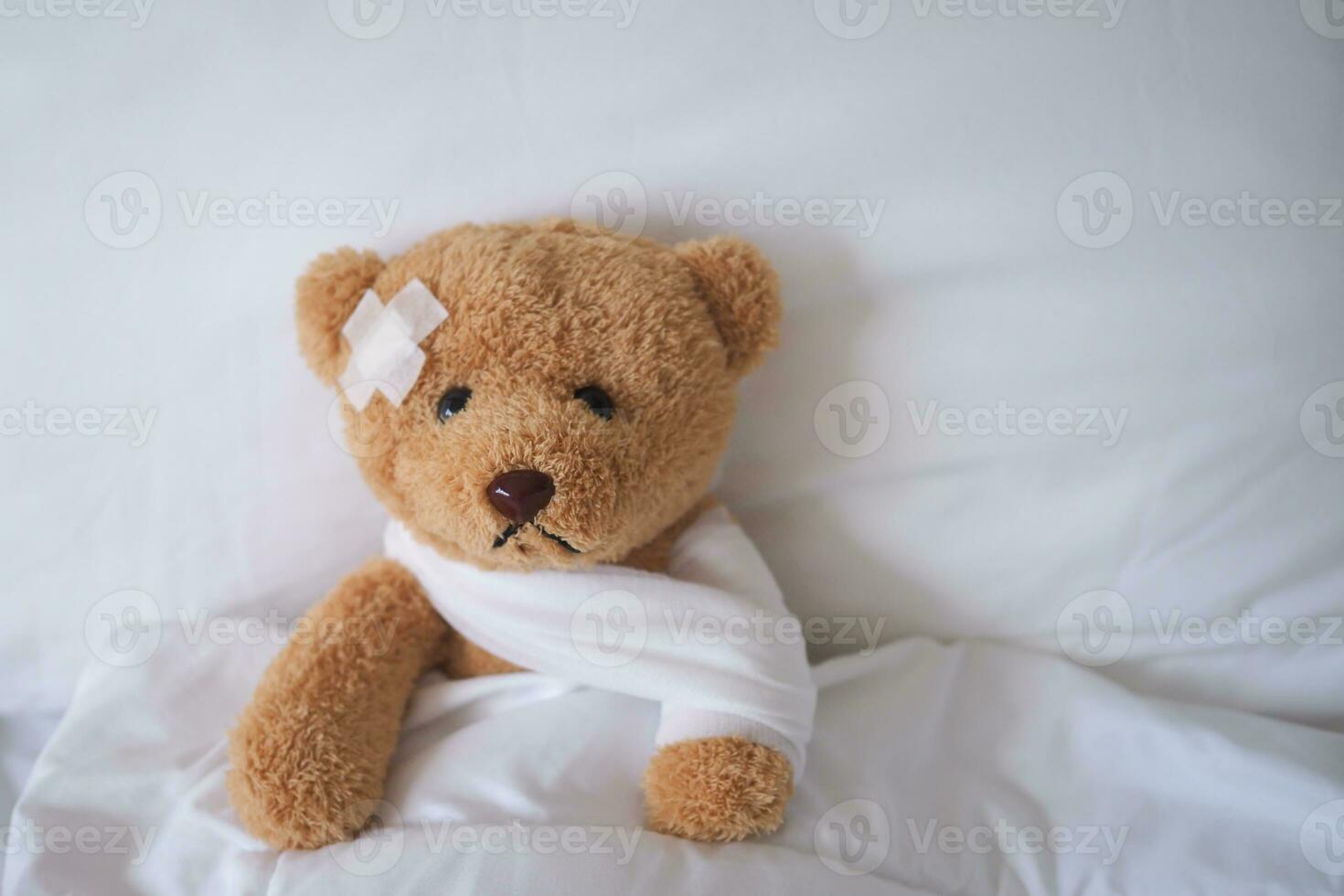 Urso com curativo, criança médico Cuidado . ferido criança Urso de pelúcia Urso e doloroso dentro hospital, caiu eu vou dentro a cama, acidente, seguro, saúde Cuidado, risco, perda, emergência, proteção, tratar, criança , bebê foto