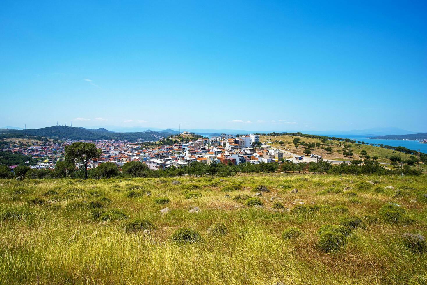 uma turco pequeno Cidade negligenciar a mar e uma verde campo em uma verão e ensolarado dia. foto