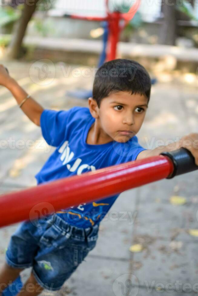 ásia Garoto fazendo rotina exercício dentro sociedade parque durante a manhã tempo. fofa pequeno criança exercício e Academia para manter ele mesmo em forma para vida. criança exercício ao ar livre tiro foto