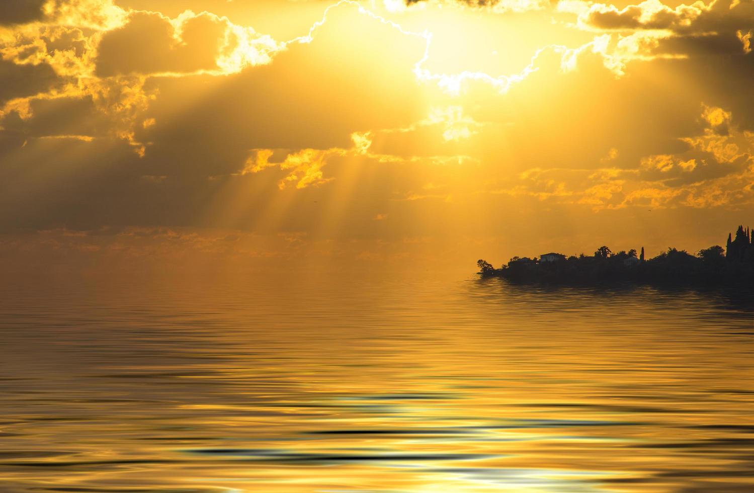vista do mar com um lindo pôr do sol e raios de sol foto