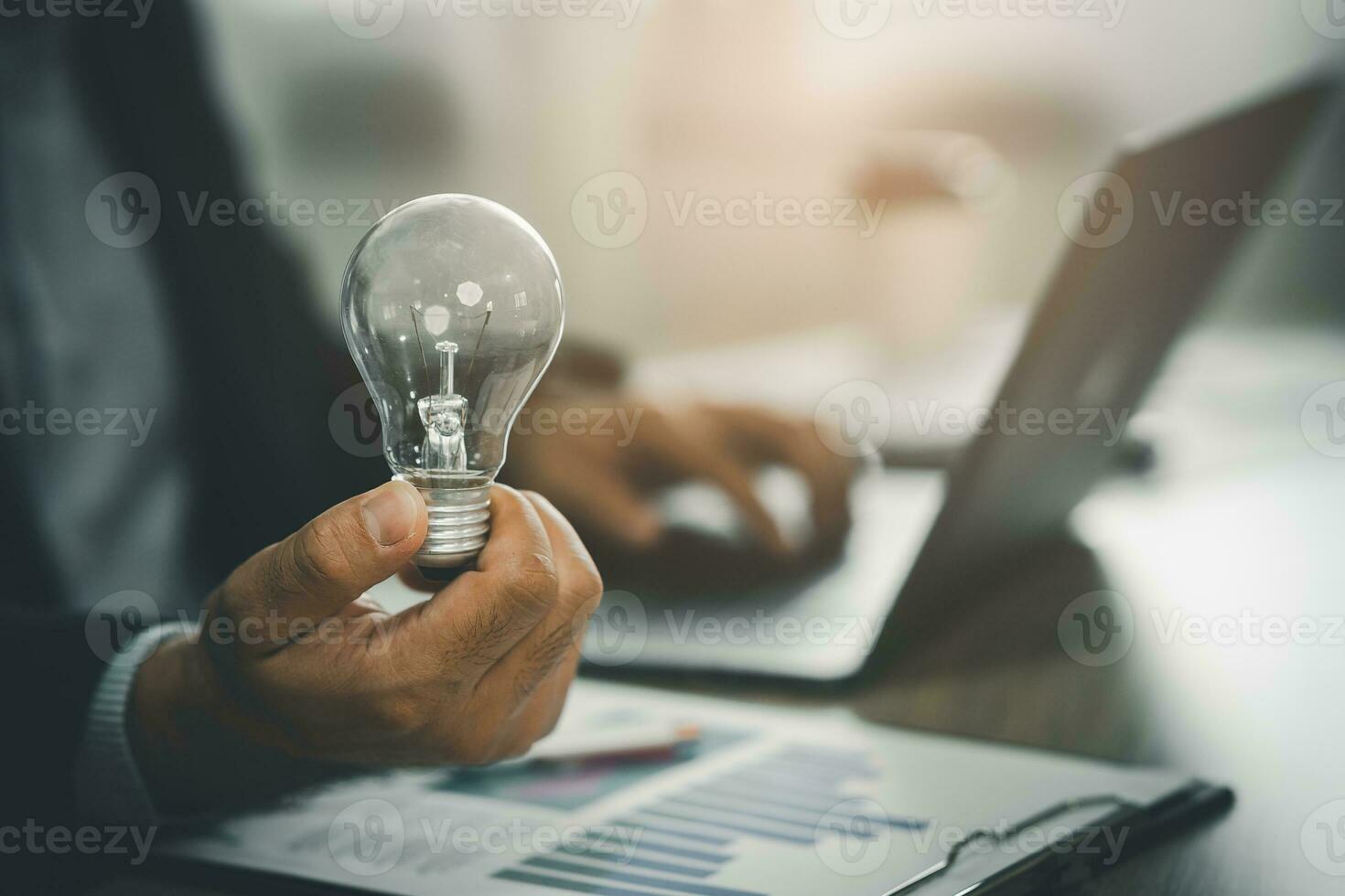 homem de negocios segurando uma brilhante luz lâmpada e trabalhando com computador portátil em a escrivaninha. conceito do Ideias para apresentando Novo Ideias ótimo inspiração e inovação Novo começo. foto