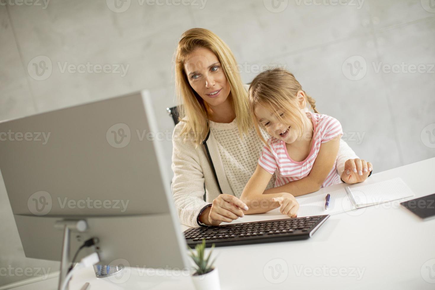 mãe tentando trabalhar com a filha foto