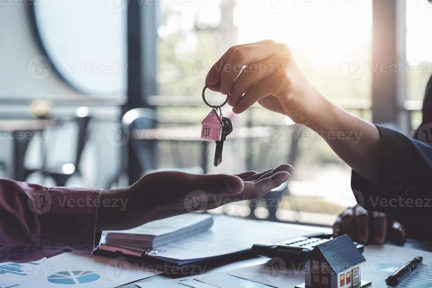 os corretores imobiliários concordam em comprar uma casa e dar as chaves aos clientes nos escritórios de suas agências. acordo de conceito foto