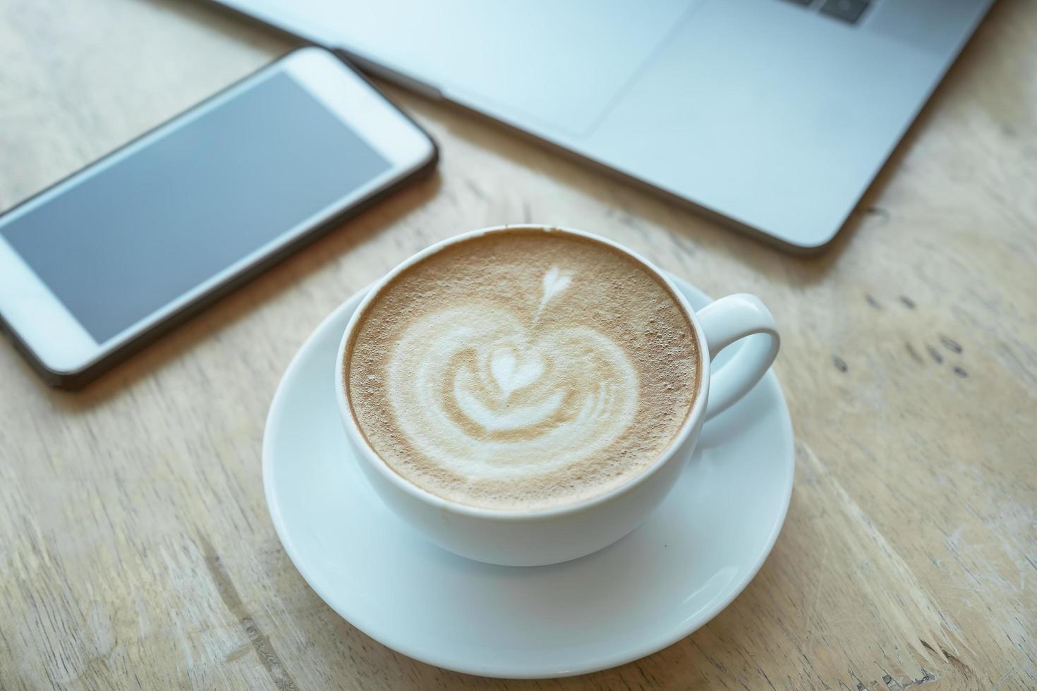 Cuide de sua xícara de café de conceitos de saúde na mesa de madeira com smartphone e laptop no escritório foto