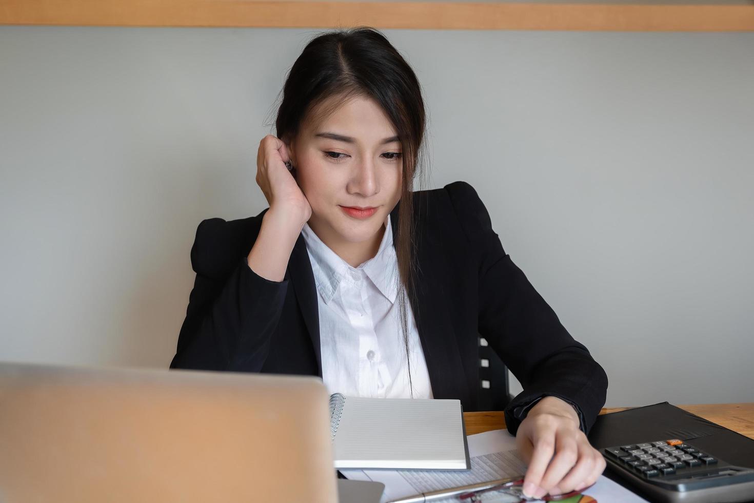 uma mulher de negócios ou contadores estão trabalhando no escritório para verificar a exatidão da conta usando uma calculadora e um laptop foto