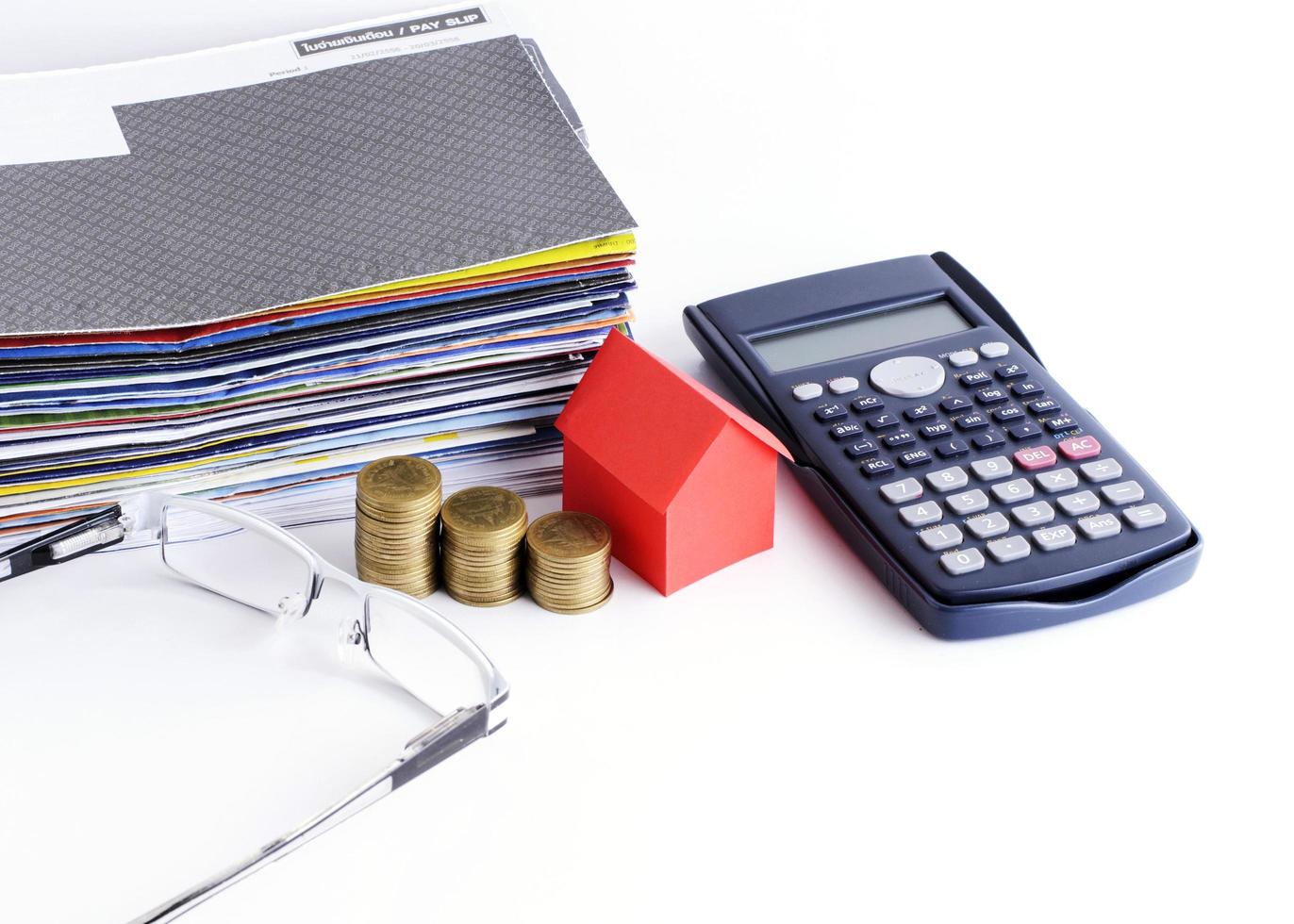 conceito de empréstimos com close-up do papel da casa e pilha de moedas com calculadora e óculos para o conceito de pagamento de contas foto