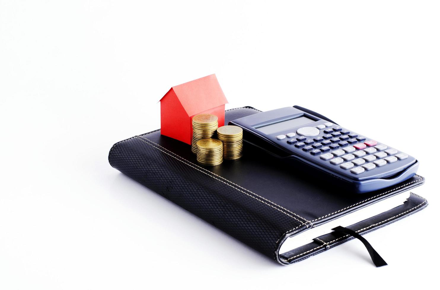 calculadora e livro de negócios com pilha de moedas e papel da casa vermelha para o conceito de empréstimos foto