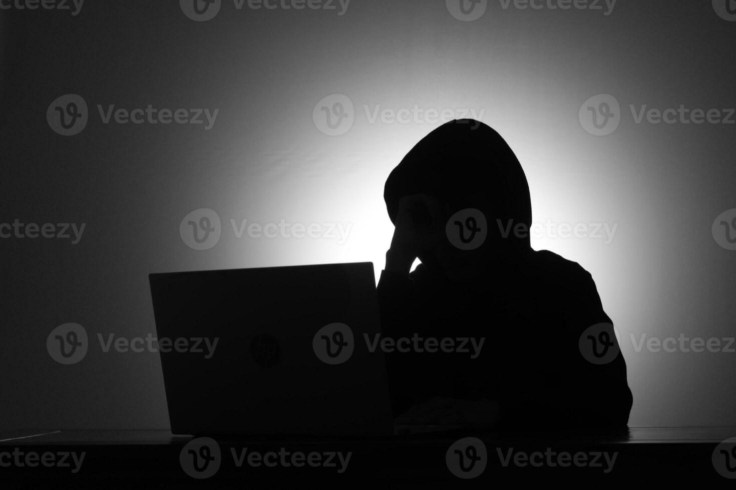 misterioso homem vestindo Preto moletom com capuz usando computador portátil e segurando crédito cartão dentro a Sombrio sala. hacker e cyber segurança conceito. foto