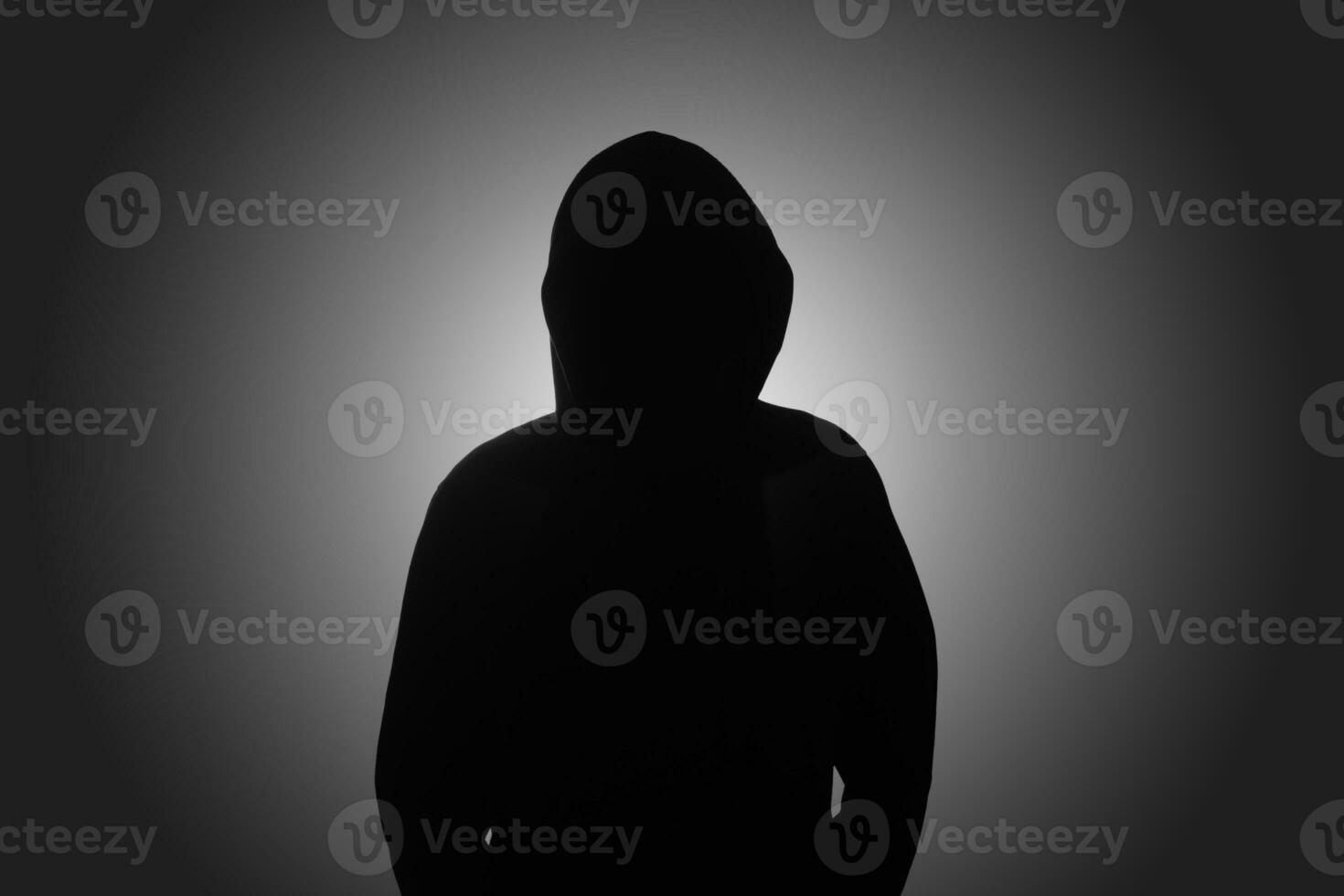 misterioso homem vestindo Preto moletom com capuz em pé contra Sombrio fundo. hacker, crime, e cyber segurança conceito. foto