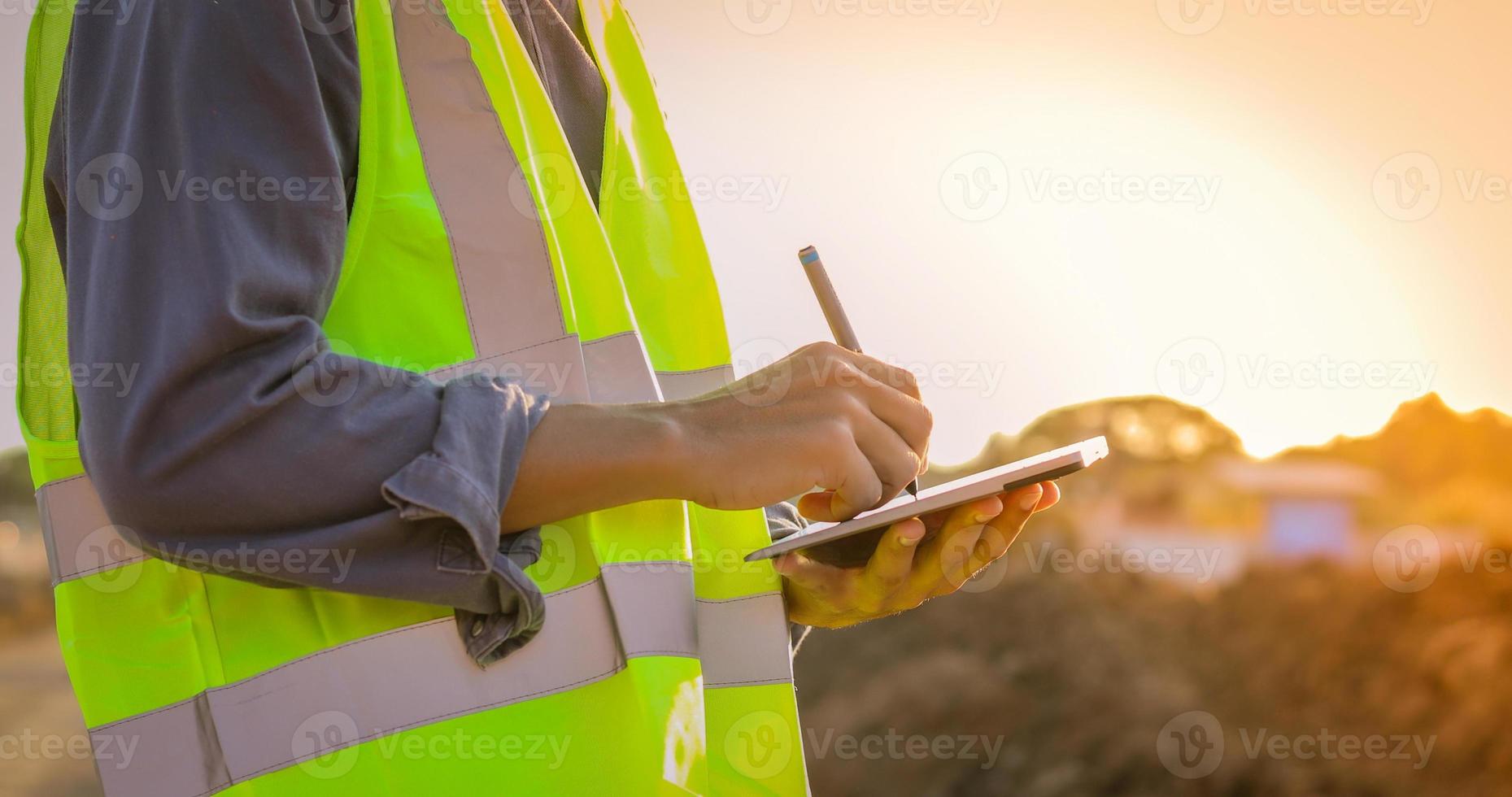 faixa do homem com colete de segurança escrevendo no tablet digital foto