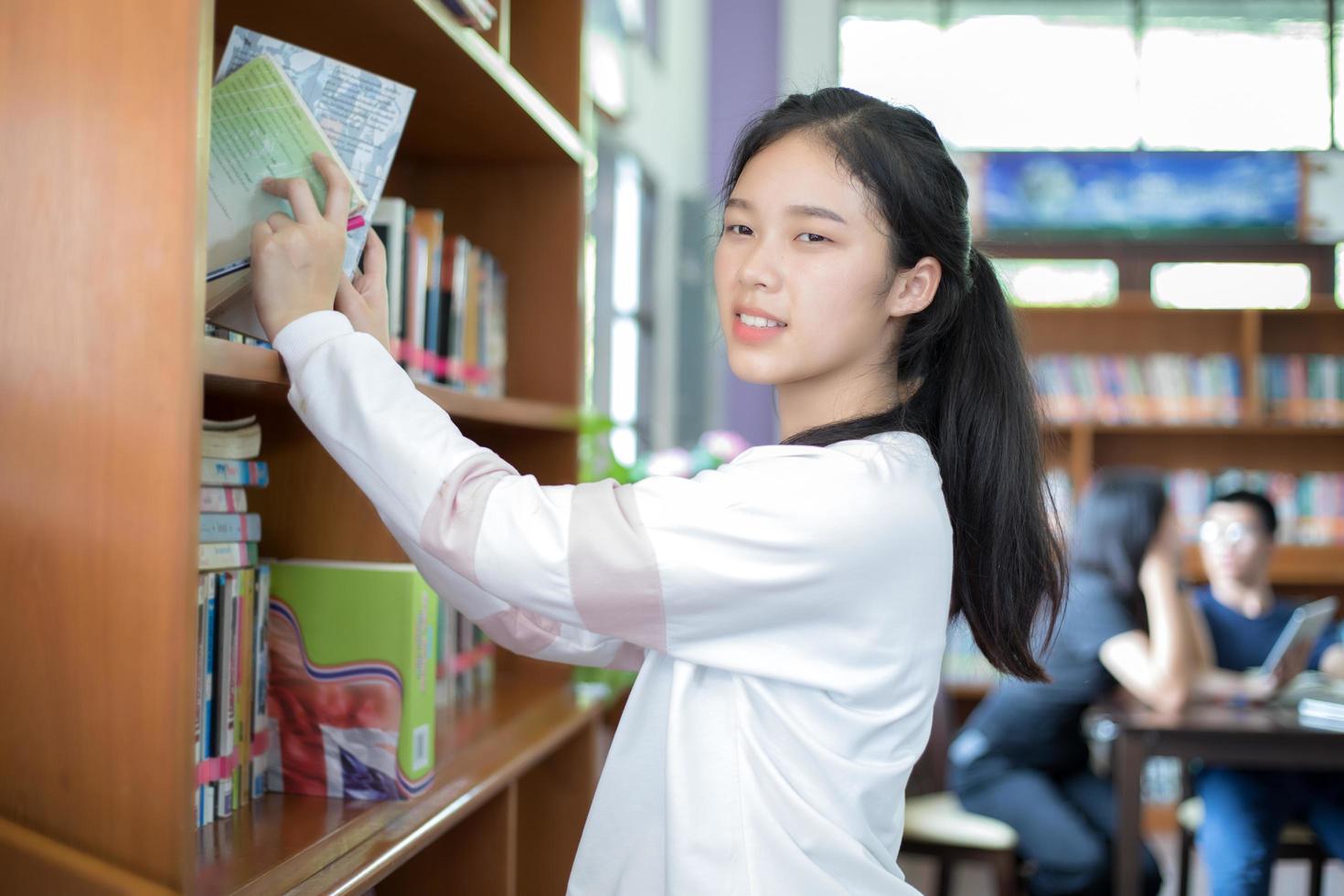 aluna encontrando livros na biblioteca foto