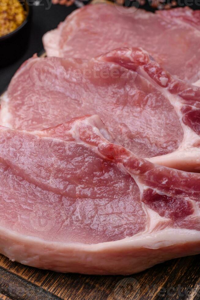 cru carne de porco em a osso ou costela fatiado com sal, especiarias e ervas foto