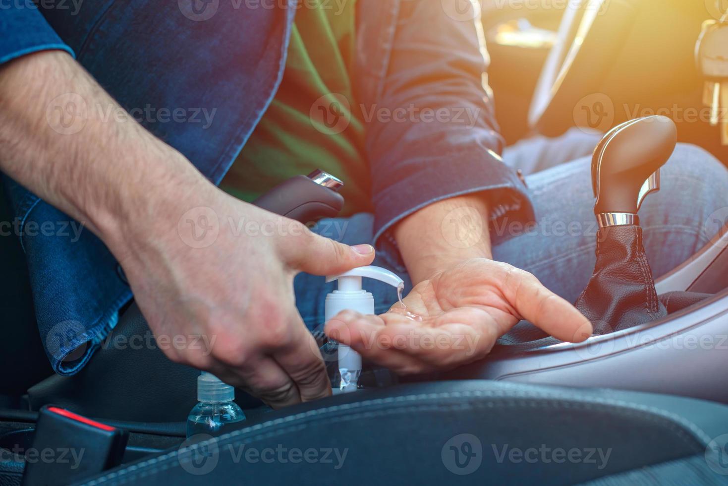 homem sentado no carro desinfeta as mãos para evitar infecção por coronavírus foto