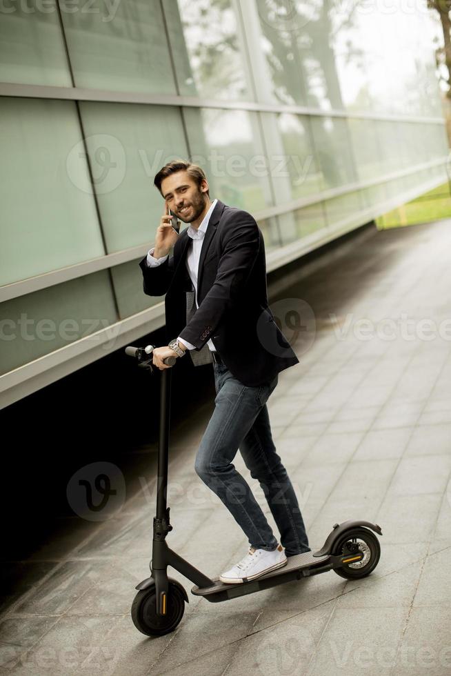 homem andando de scooter enquanto fala ao telefone foto