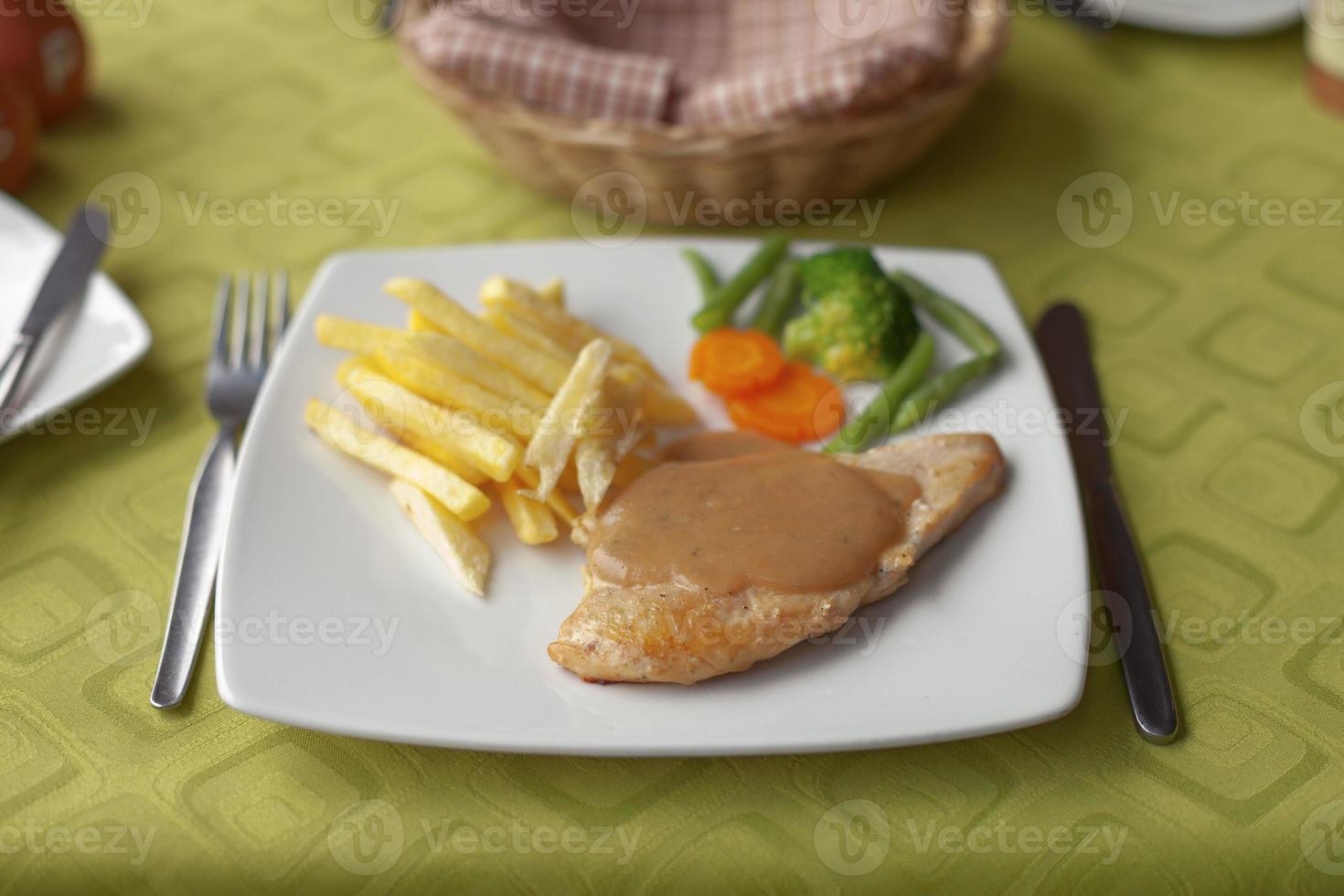 frango grelhado com molho de colca, batata frita e salada de legumes foto