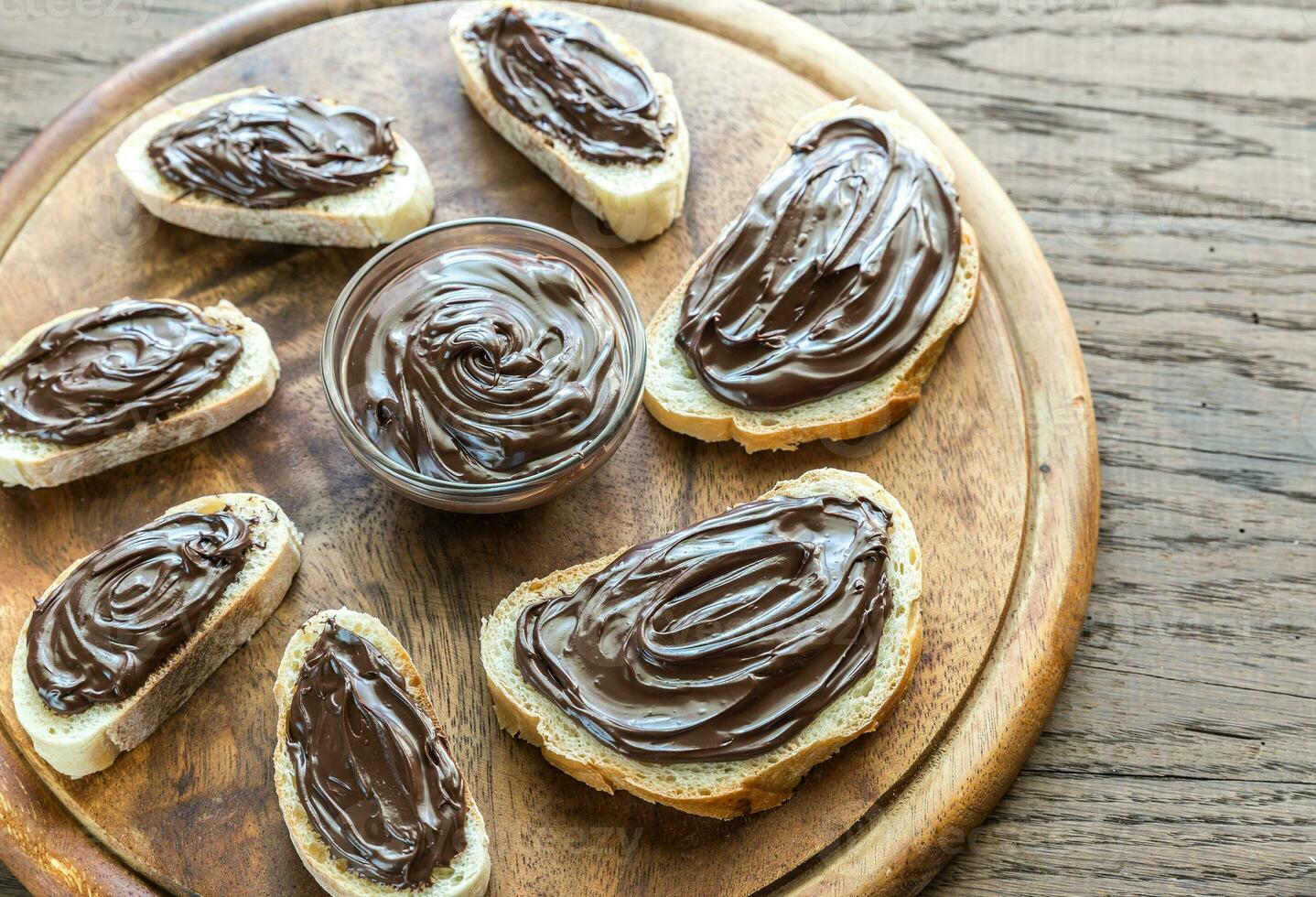 fatias de baguete com creme de chocolate na placa de madeira foto