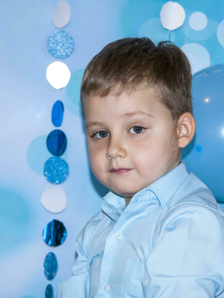 retrato do uma bonito jovem cara. retrato do uma garoto. uma Garoto dentro uma azul camisa em uma azul festivo fundo. foto