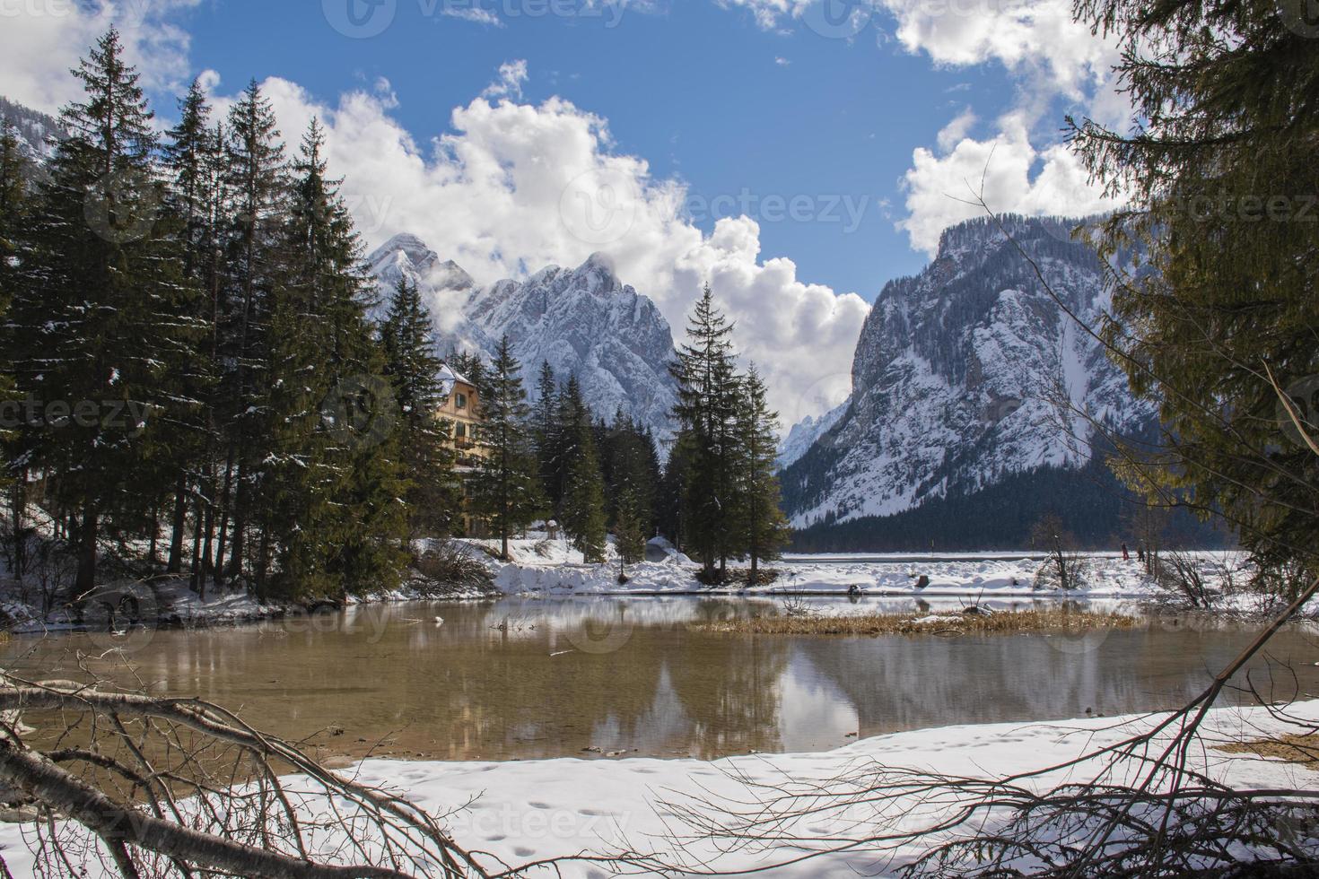 lago alpino entre floresta e montanhas cobertas de neve foto