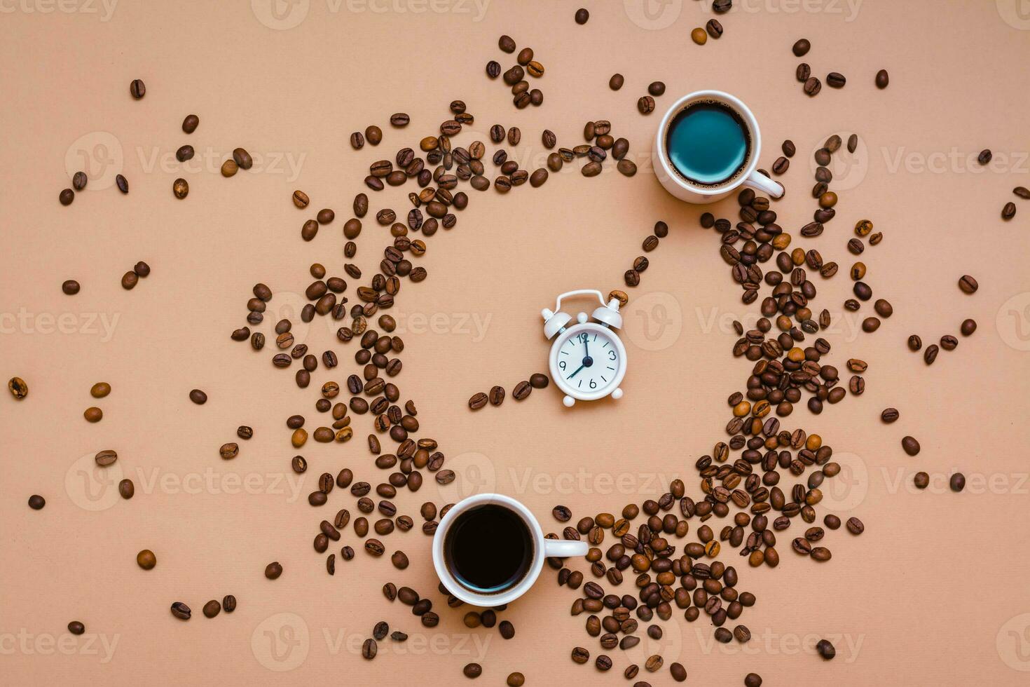 dois copos do Preto café dentro uma círculo a partir de café feijões e uma branco alarme relógio em uma bege fundo. Tempo para beber café conceito. topo Visão foto