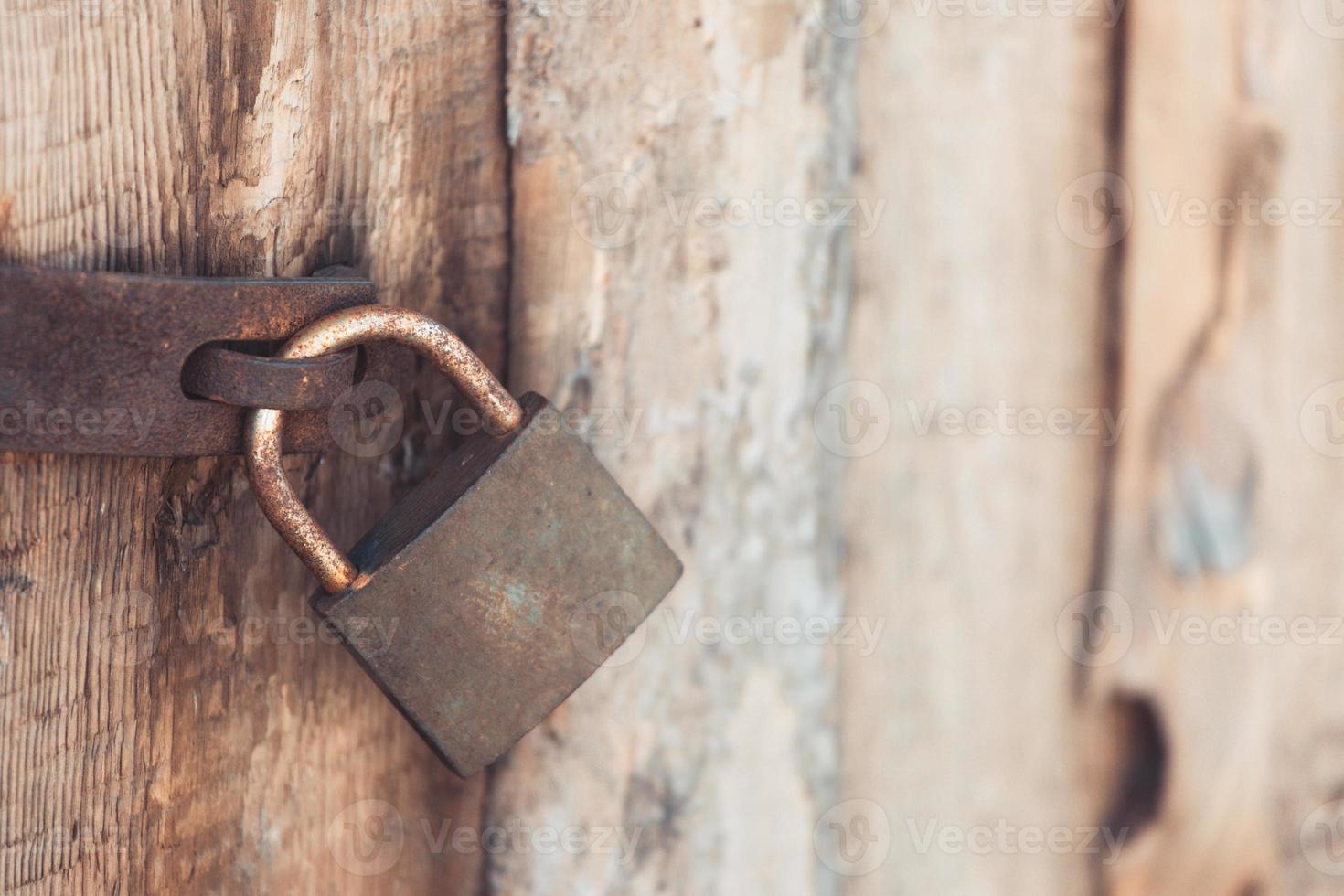 o cadeado de metal antigo e vintage com ferrugem na porta de madeira trancada para segurança foto